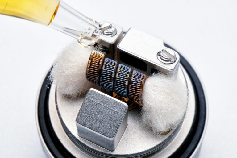 Detailed macro shot of a vape coil being primed with e-liquid, showcasing technology and craftsmanship.