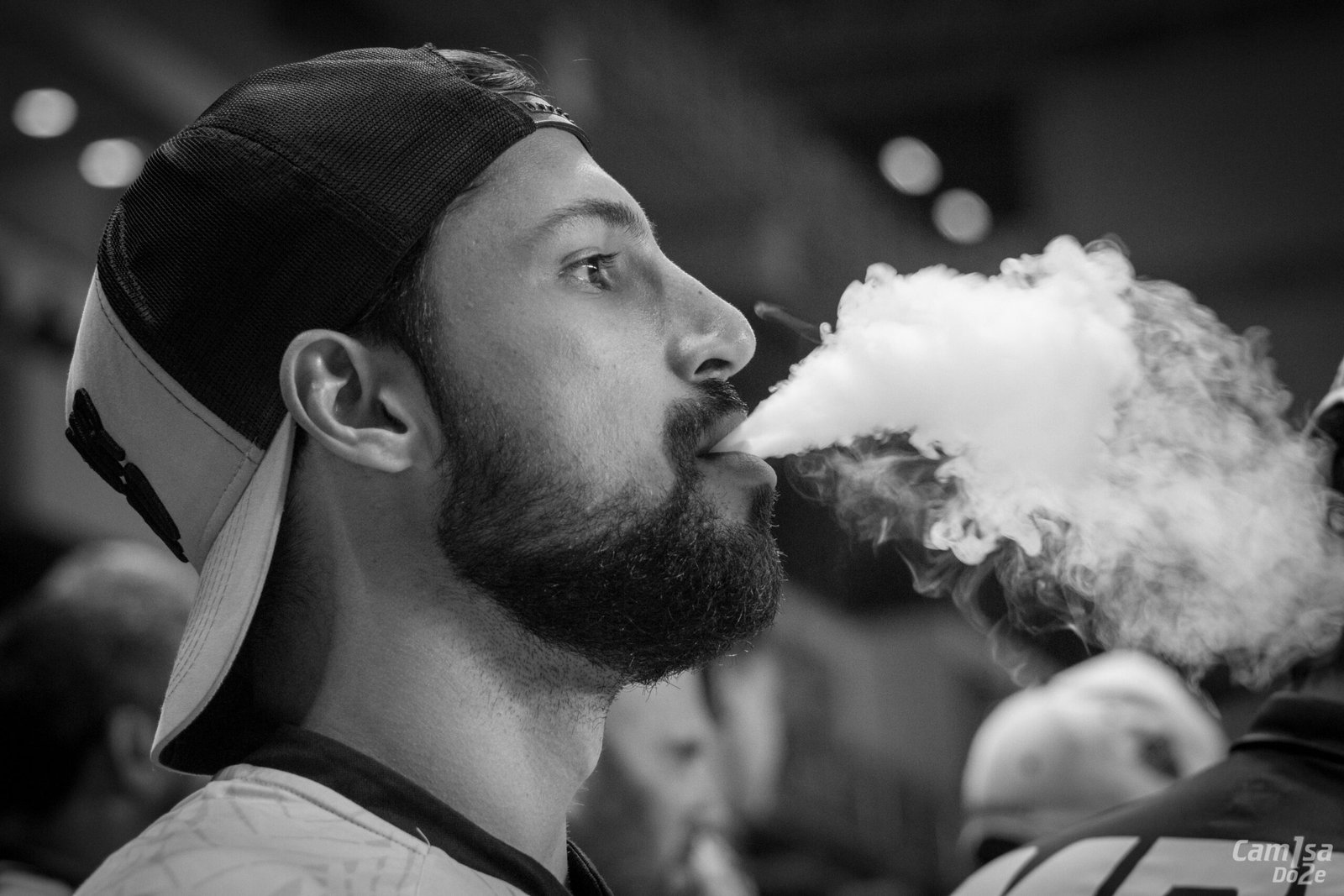 Artistic black and white close-up of a man exhaling vapor, emphasizing modern lifestyle.